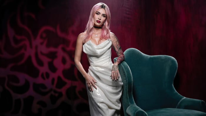 Megan Fox in a white dress leaning on a chair