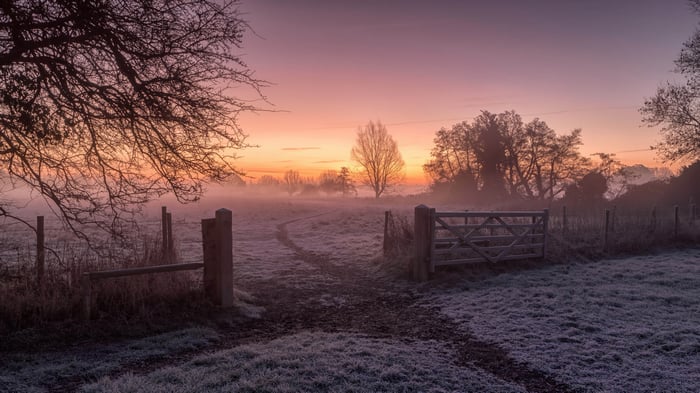 Misty Sunrise Over a Frosty Field with a Gate