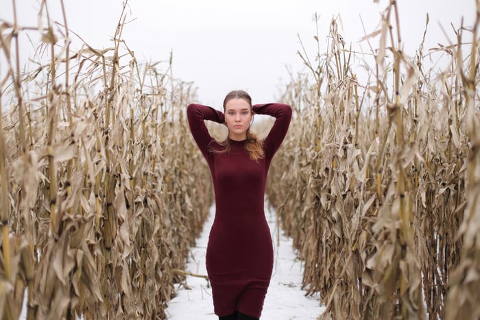 Woman in red dress in a dry cornfield