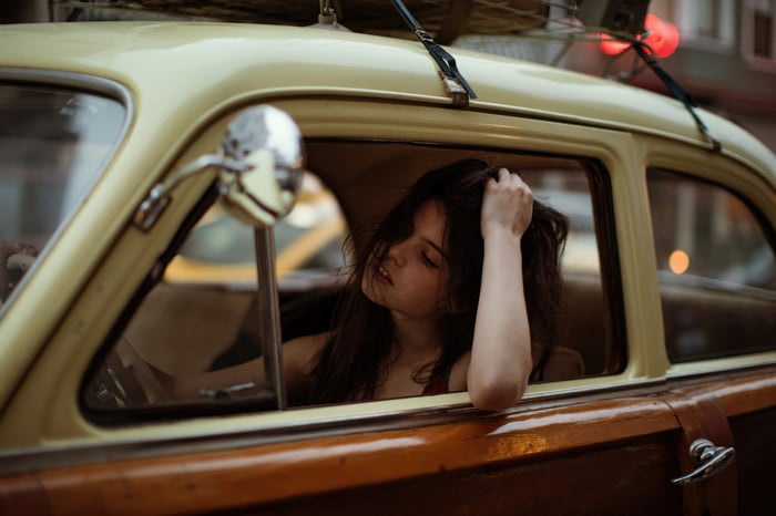 Girl in vintage car with luggage on roof