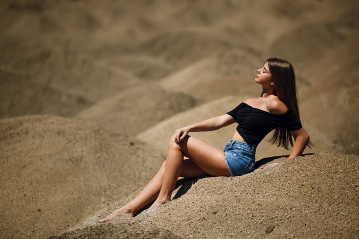Girl in jean shorts sitting in a desert