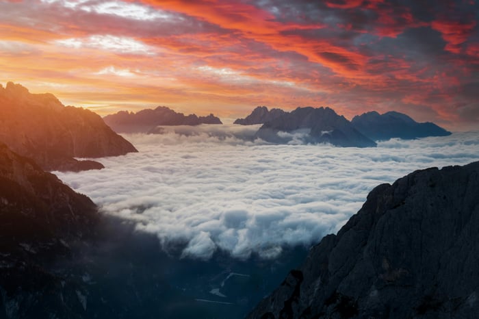 Mountain peaks above clouds during a dramatic pink sky sunset