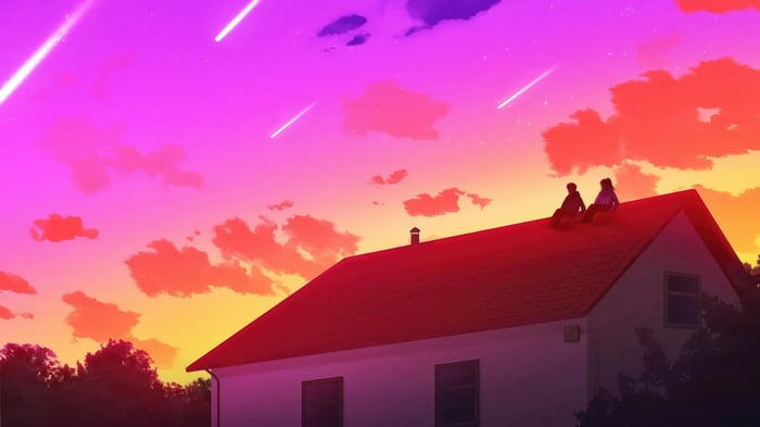 Two people sitting on a rooftop at sunset