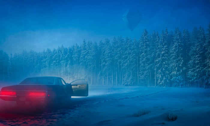 Car with hazard lights on in a snowy forest at night