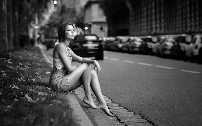 Girl sitting on curb smoking cigarette