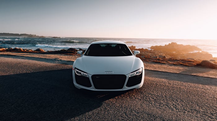White Audi R8 parked by the ocean at sunset