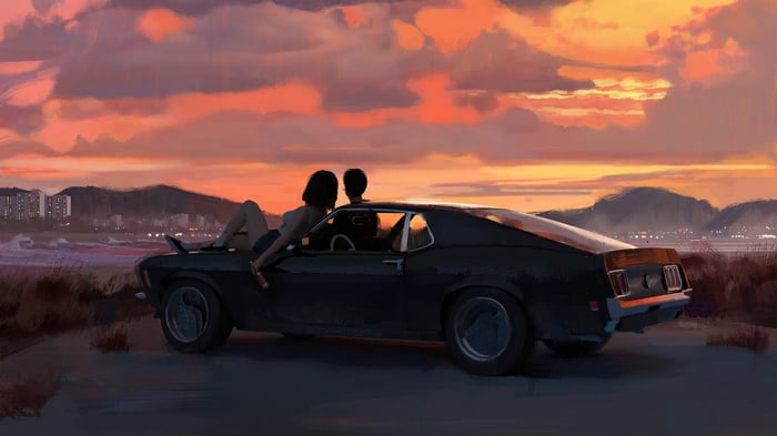 Couple watching sunset by the beach in a classic car