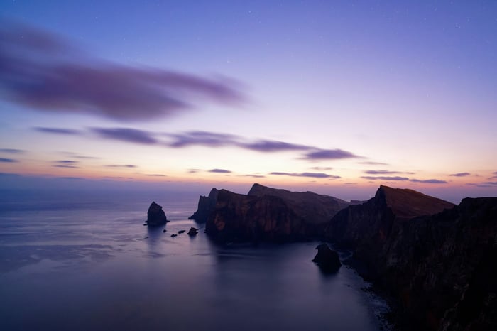 Rocky coastline at twilight with stars in the sky