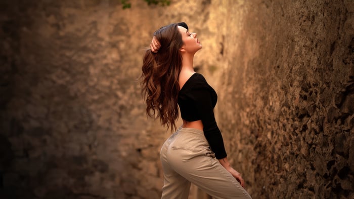 Woman with long brown hair touching her hair