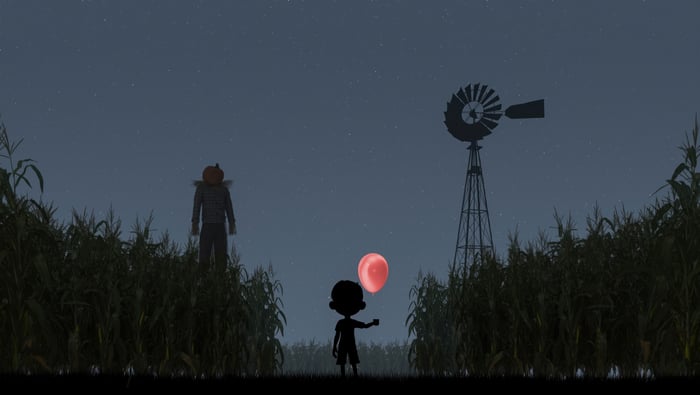 Silhouette of a boy with a red balloon in a cornfield at night