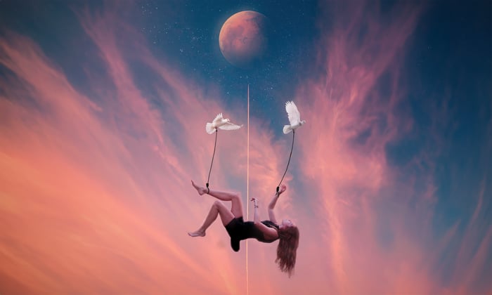Woman suspended by doves against a surreal sky