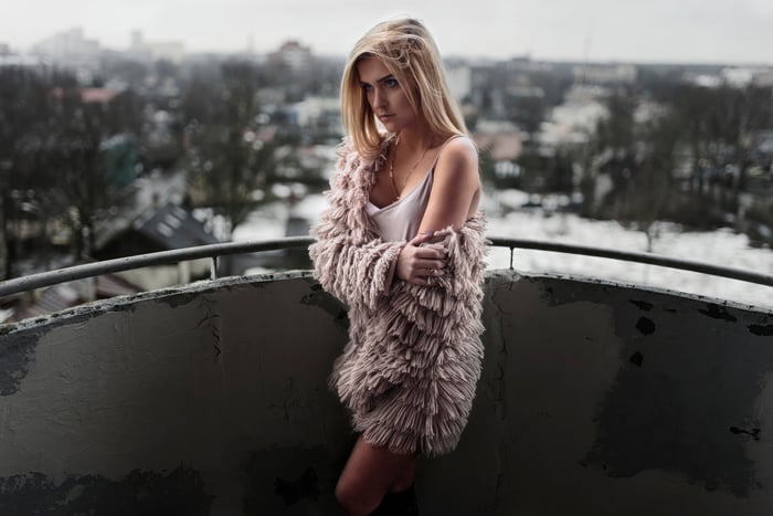 Girl in a fluffy coat on a balcony overlooking a city