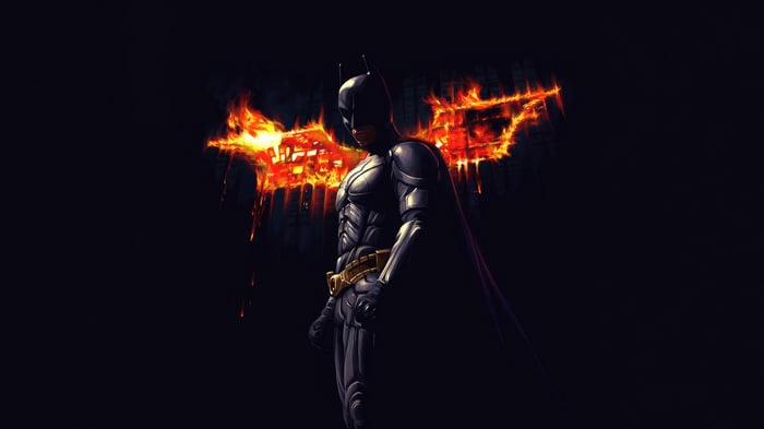 Batman standing in front of a burning Bat-Signal