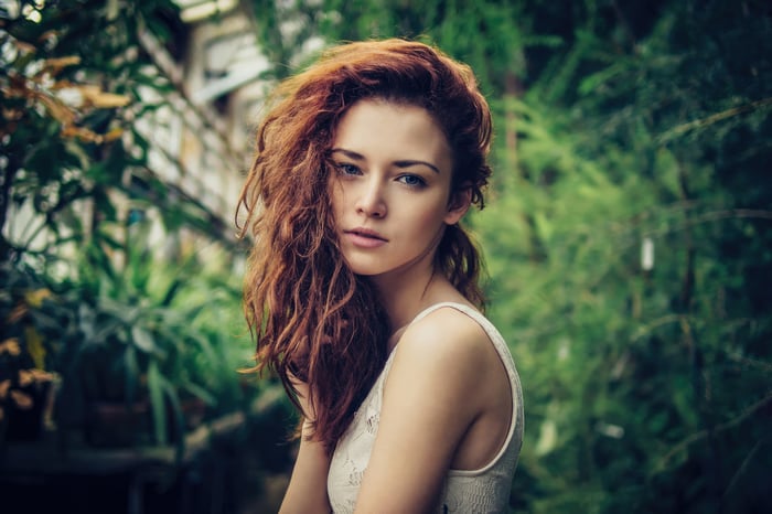 Young woman with red curly hair in a garden