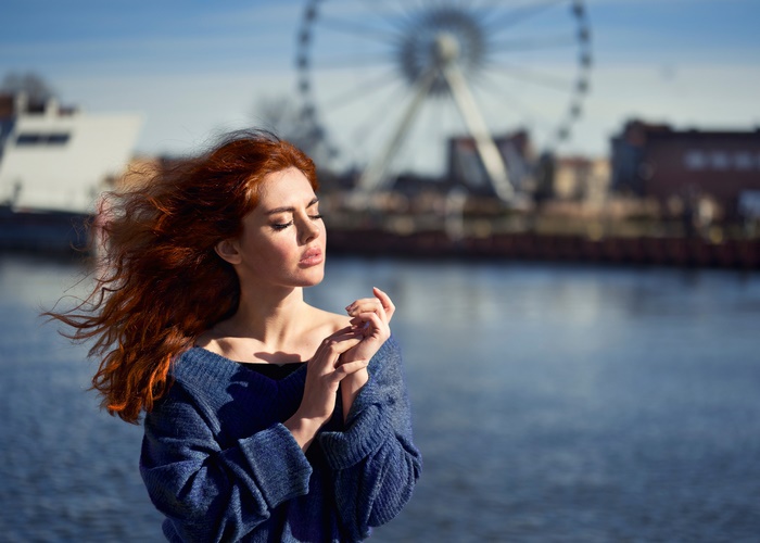 Redhead woman with windblown hair by the water