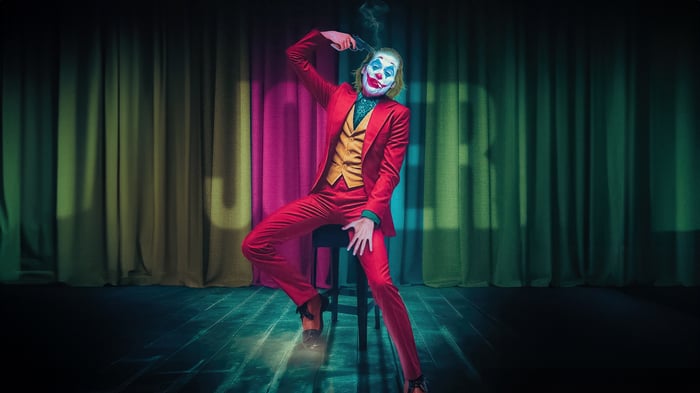 Joker sits on a stool with a gun to his head