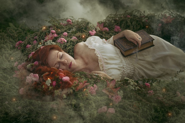 Redhead woman sleeping with a book in a garden