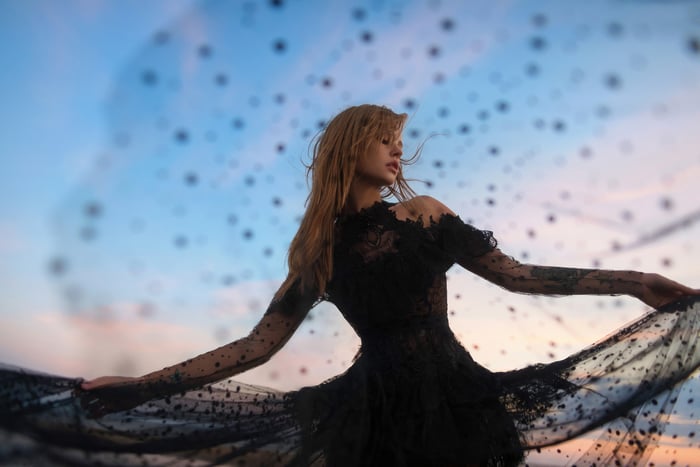Girl in black web dress against a sunset sky