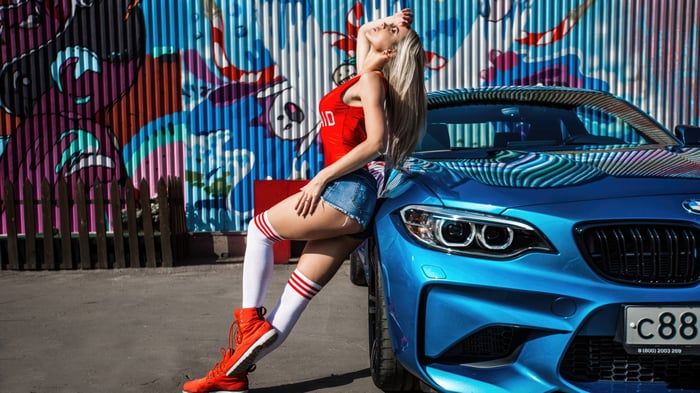 Girl leaning on a blue BMW car