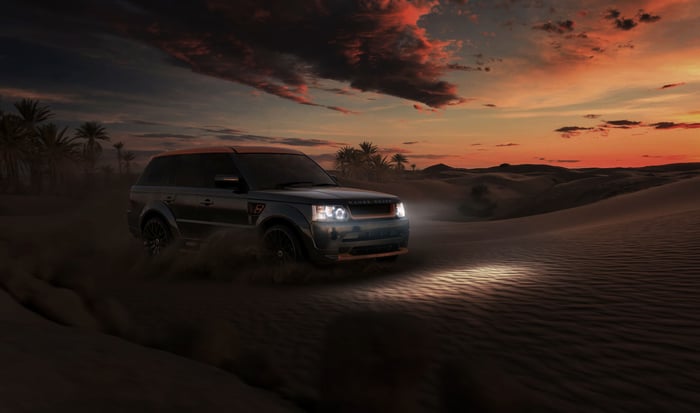 Range Rover driving through desert at sunset