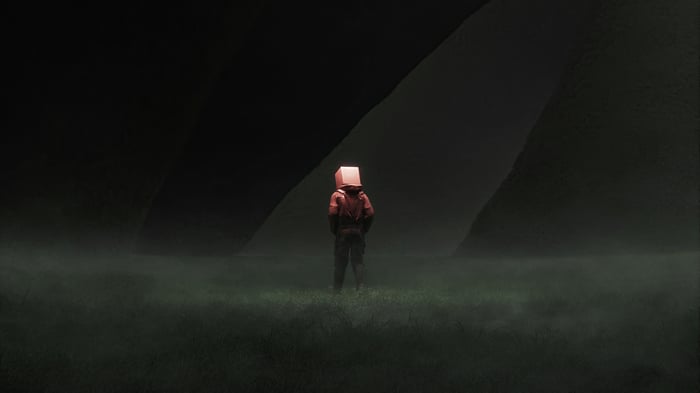 Person with a box on head in a dark landscape