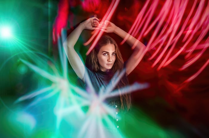 Girl with arms raised amidst colorful light streaks