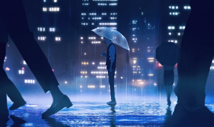 A lone figure with an umbrella in the rain at night