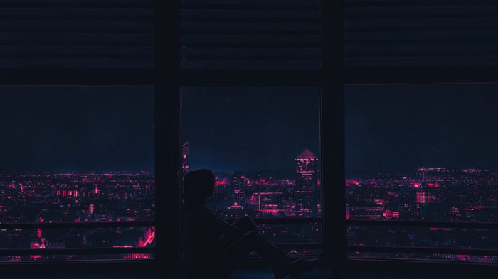 Person looking out at a neon city at night