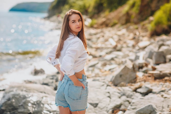 Girl with hands in back pocket on a rocky beach