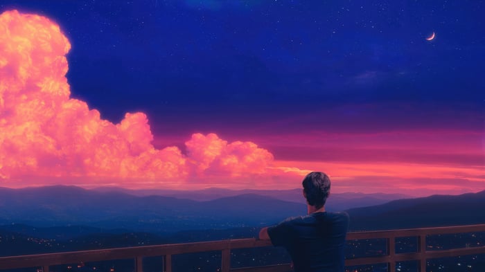 Man Gazing at a Colorful Sunset Over Mountains