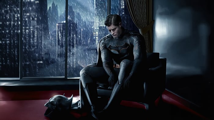 Jensen Ackles as Batman sitting in a chair