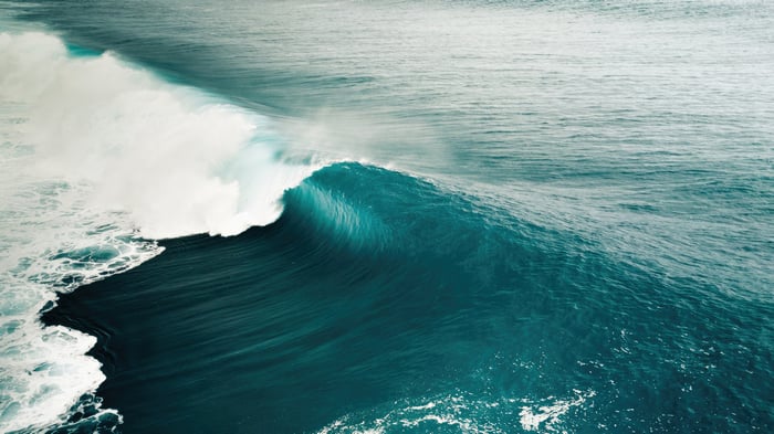 A large ocean wave breaks with white foam