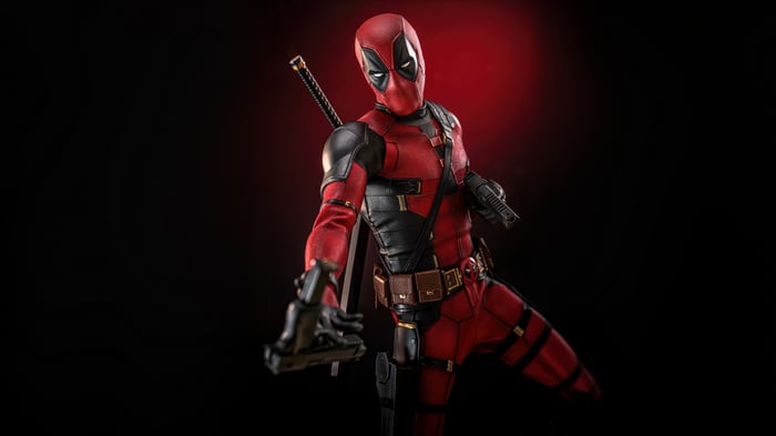 Deadpool holding a gun with swords on his back