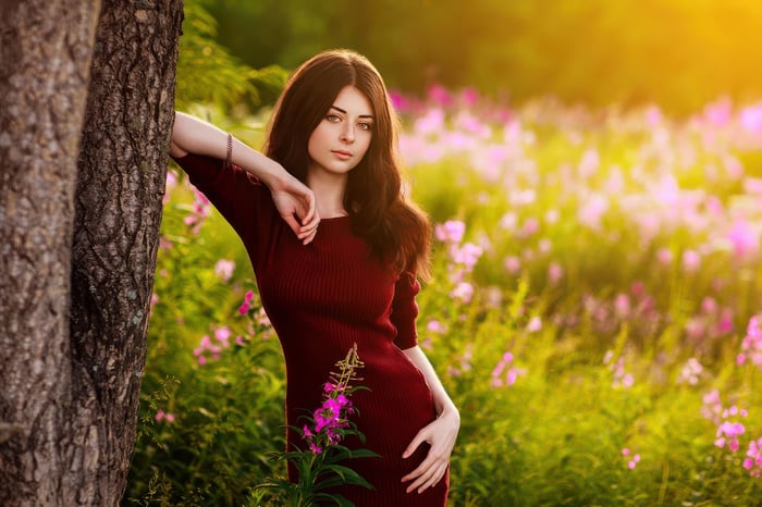Cute Girl Leaning on Tree in Flower Field