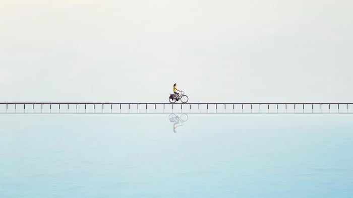 Person riding a bicycle on a bridge over water
