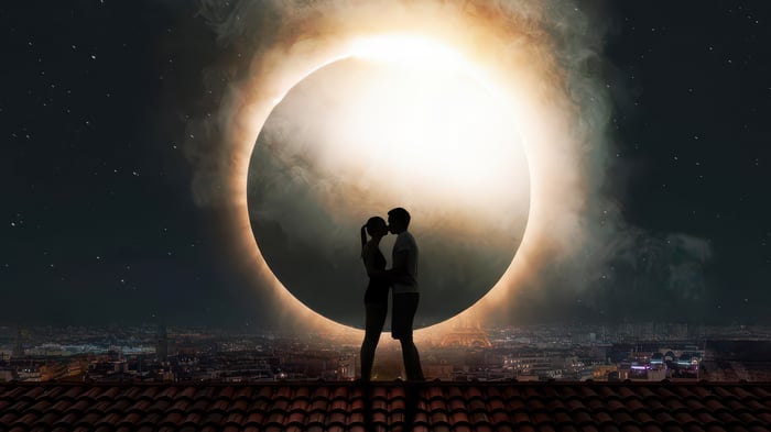 Couple kissing during a solar eclipse over a city