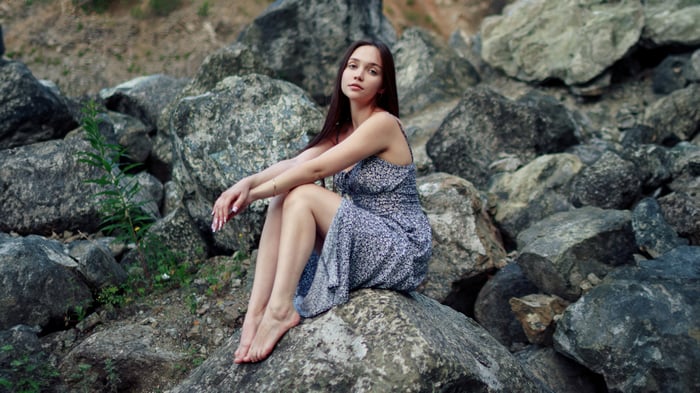 Girl sitting barefoot on rocks