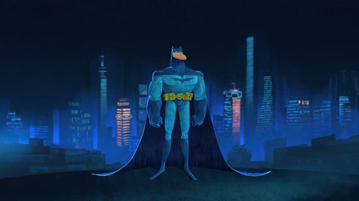 Batman stands in a city at night