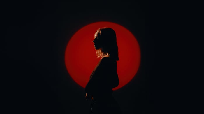 Girl silhouetted against a red circle in a dark room