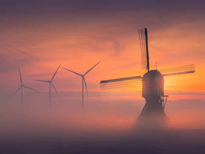 Windmill and wind turbines at sunset in fog