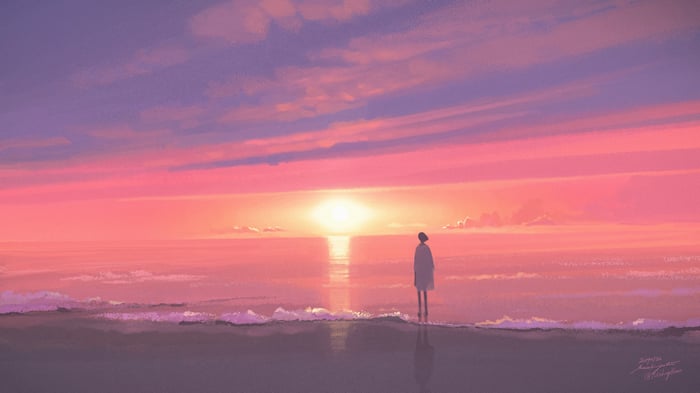 A person stands on a beach at sunset