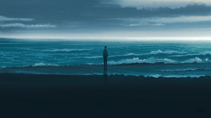 A lone figure stands on a beach facing the ocean