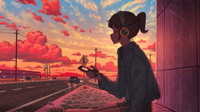 Girl with headphones listening to music at sunset