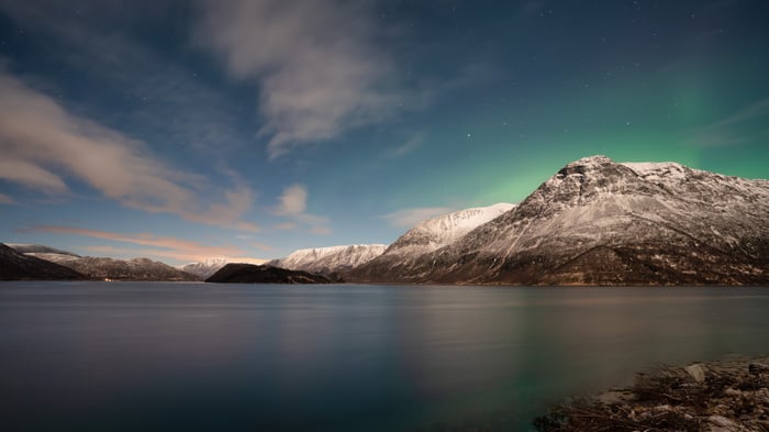 Aurora Borealis over snow-capped mountains and a lake