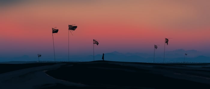 Silhouette of a person standing alone with flags at sunset