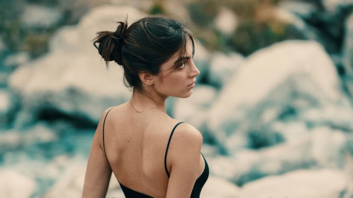 Woman with dark hair wearing a black dress and necklace