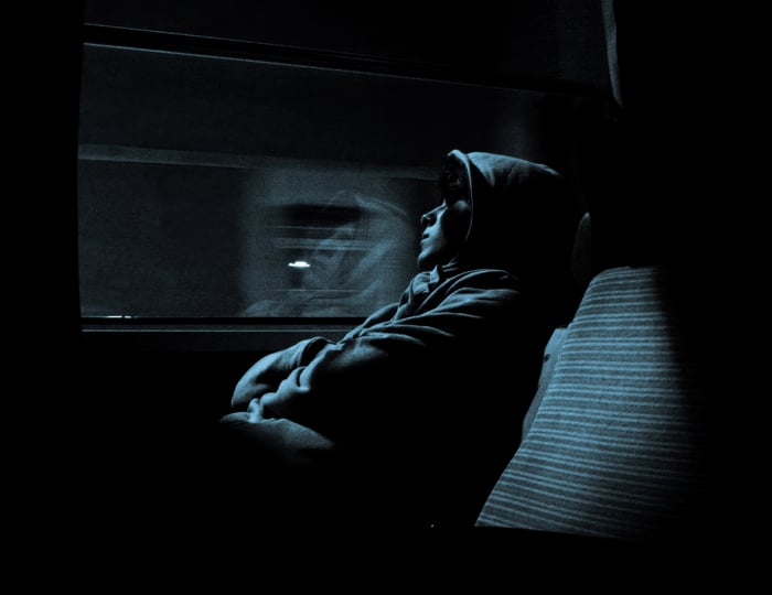 Boy in hoodie looking out train window at night