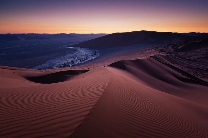 Sand dunes at sunset with purple and orange sky