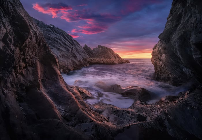 Rocky coastline at sunset with colorful clouds