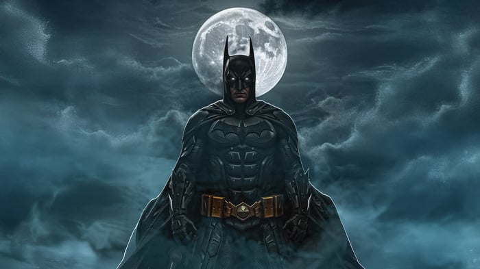 Batman stands before a full moon in dark clouds